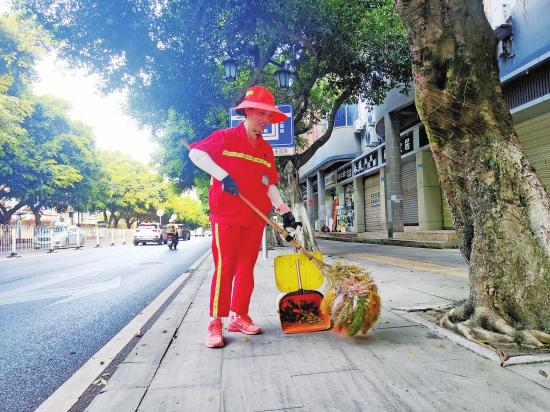 环卫工人周丽琼清扫人行道路面垃圾。